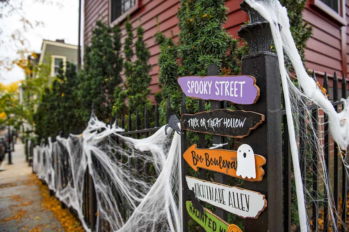 Spend Halloween in Boston on the spooky Beacon Hill. Image shows spooky halloween signs on a fence in Boston.